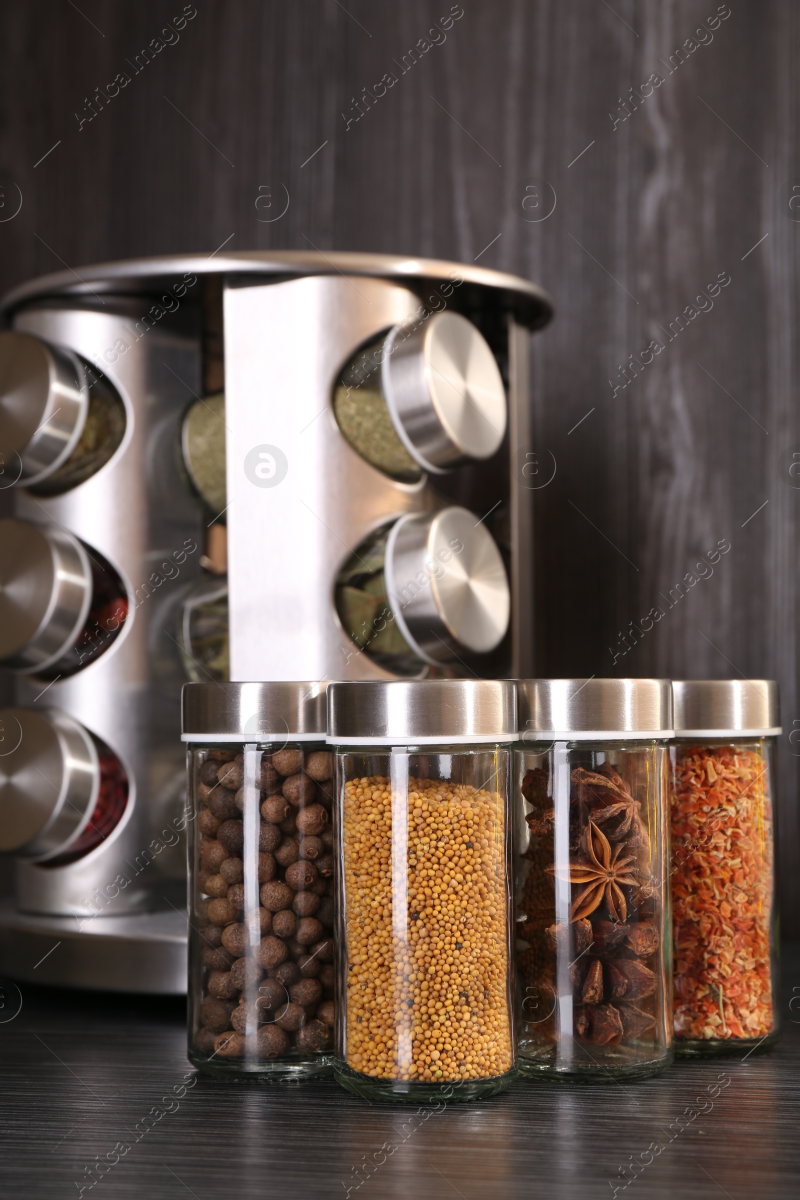 Photo of Different spices in glass jars on grey wooden table