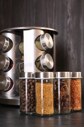 Photo of Different spices in glass jars on grey wooden table