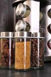 Photo of Different spices in glass jars on grey wooden table, closeup