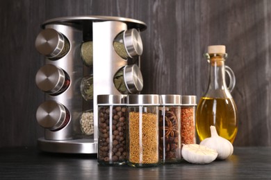 Photo of Different spices in glass jars on grey wooden table