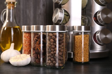 Photo of Different spices in glass jars on grey wooden table, closeup