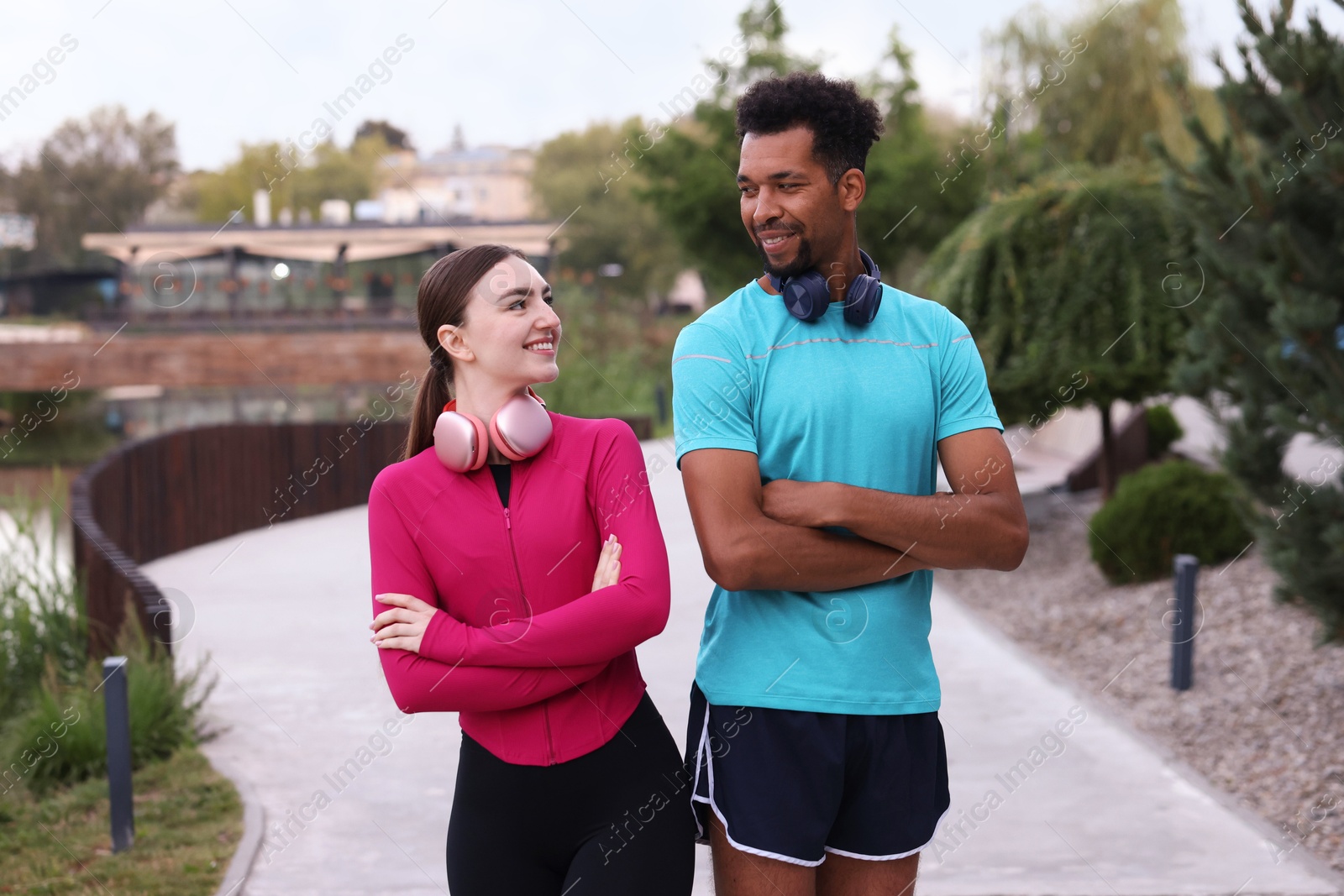 Smiling runners with headphones posing with crossed arms outdoors Photo of Smiling runners with headphones posing with crossed arms outdoors