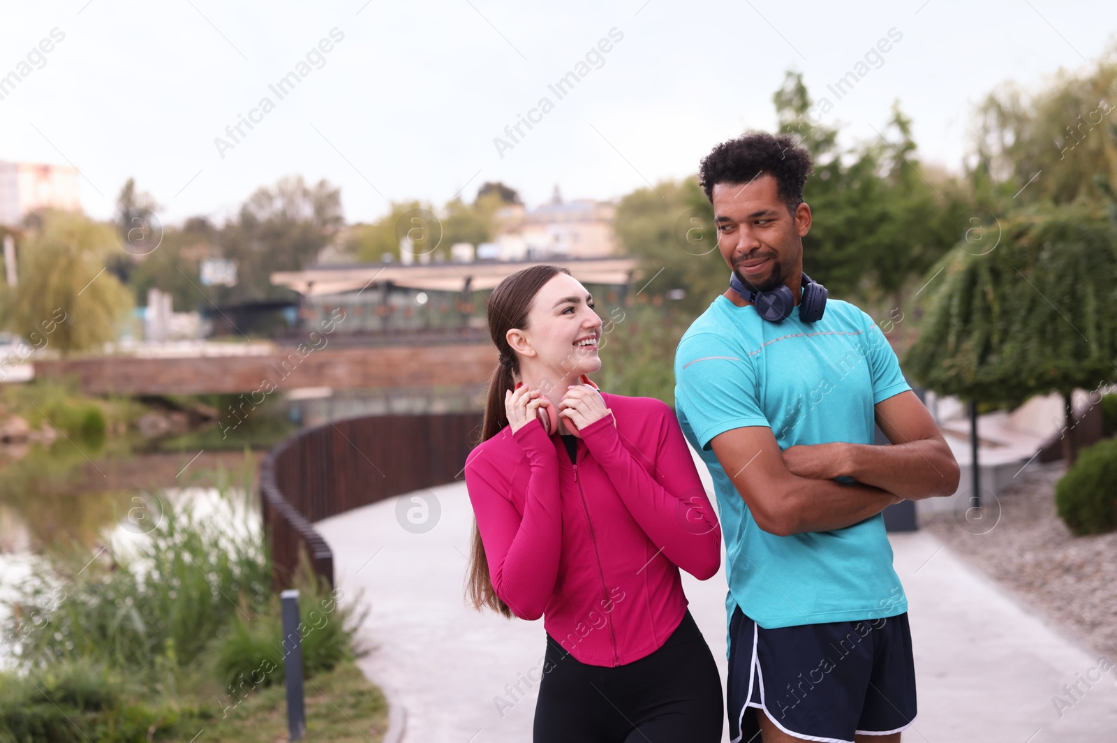 Photo of Smiling runners with headphones outdoors. Space for text