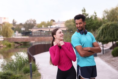 Photo of Smiling runners with headphones outdoors. Space for text