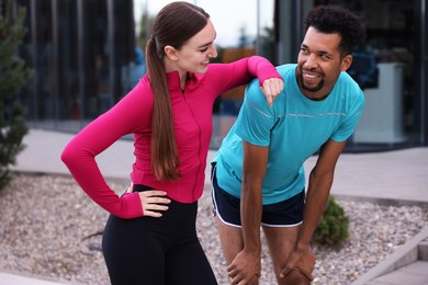 Photo of Smiling runners in sportswear spending time together outdoors