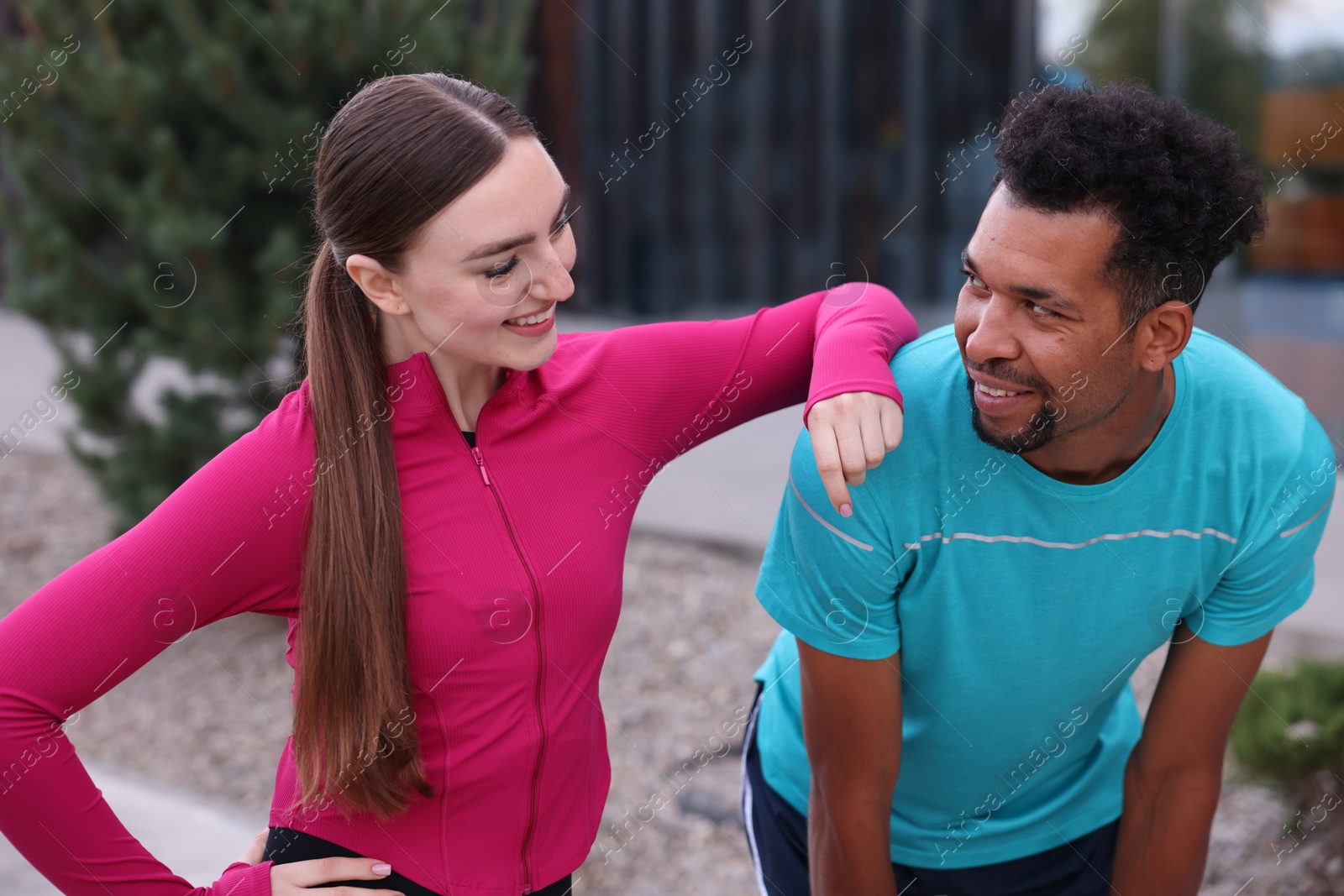 Photo of Smiling runners in sportswear spending time together outdoors