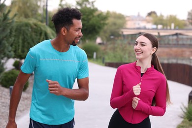 Photo of Happy couple in sportswear running outdoors. Healthy lifestyle