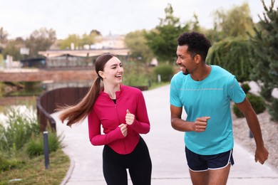 Photo of Happy couple in sportswear running outdoors. Healthy lifestyle