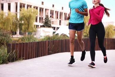 Photo of Couple in sportswear running outdoors, closeup. Space for text