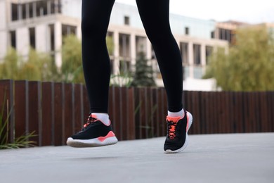 Photo of Woman in sneakers running outdoors, closeup. Healthy lifestyle