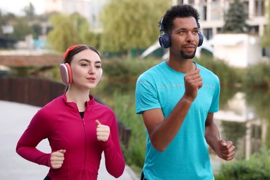 Photo of Sporty couple in headphones running outdoors. Healthy lifestyle