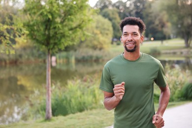 Photo of Smiling man running near river outdoors. Space for text