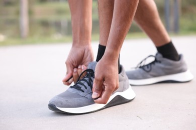 Photo of Runner tying shoelace of his sneaker outdoors, closeup