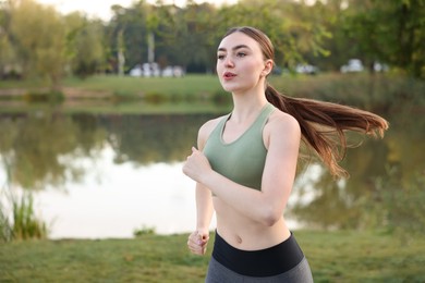 Photo of Beautiful woman in sportswear running outdoors. Space for text