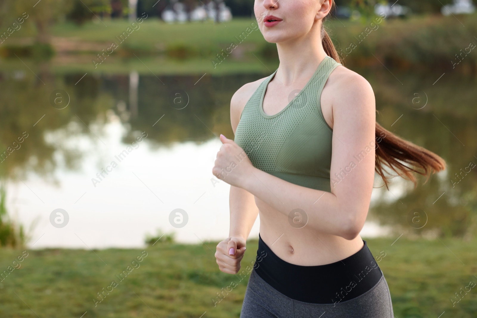Photo of Woman in sportswear running outdoors, closeup. Space for text