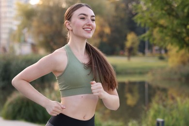 Photo of Smiling woman in sportswear running outdoors. Space for text