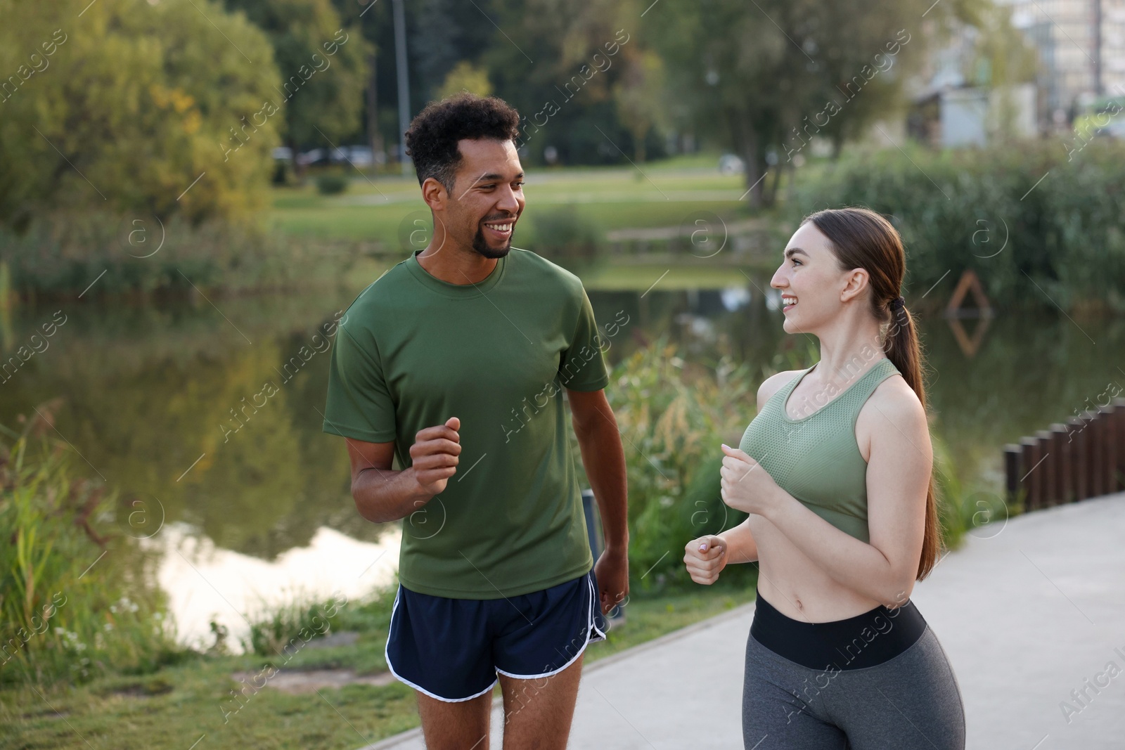 Smiling couple running near river outdoors. Healthy lifestyle Photo of Smiling couple running near river outdoors. Healthy lifestyle