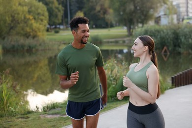 Photo of Smiling couple running near river outdoors. Healthy lifestyle