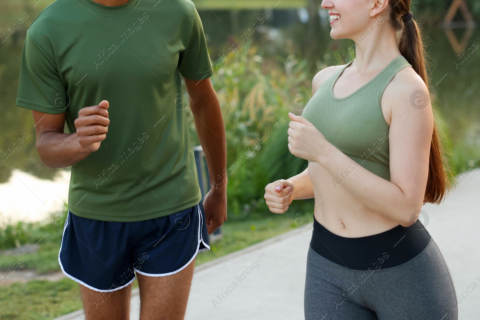 Photo of Couple in sportswear running outdoors, closeup. Healthy lifestyle