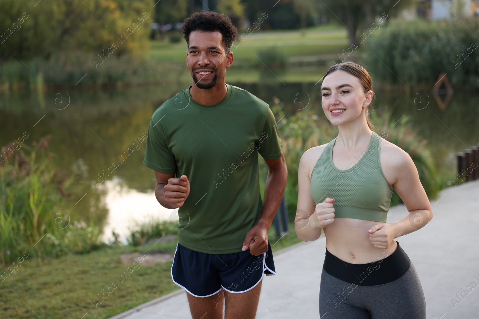 Smiling couple running near river outdoors. Healthy lifestyle Photo of Smiling couple running near river outdoors. Healthy lifestyle