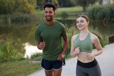 Photo of Smiling couple running near river outdoors. Healthy lifestyle