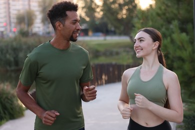 Photo of Smiling couple in sportswear running outdoors at morning