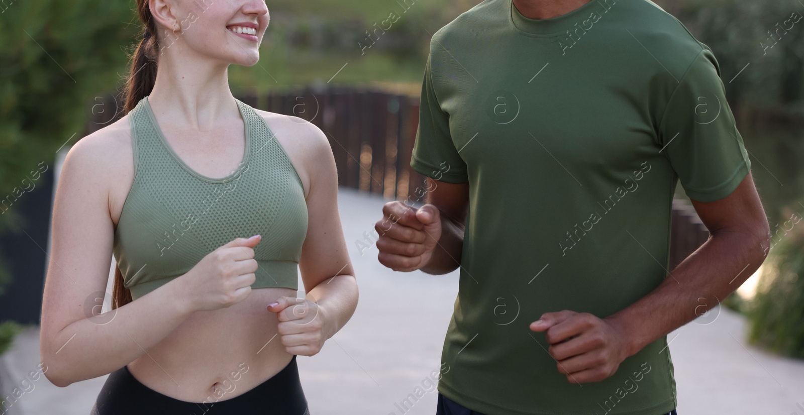 Photo of Couple in sportswear running outdoors, closeup. Healthy lifestyle