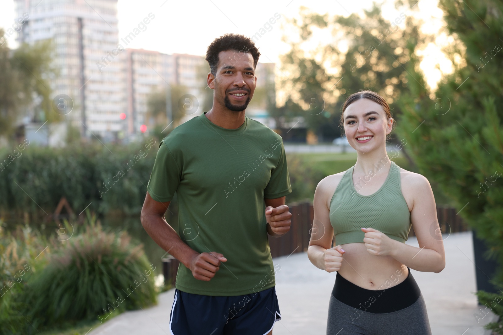 Smiling couple in sportswear running outdoors at morning Photo of Smiling couple in sportswear running outdoors at morning