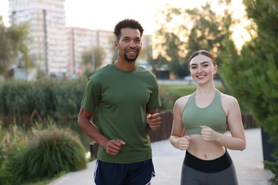 Photo of Smiling couple in sportswear running outdoors at morning