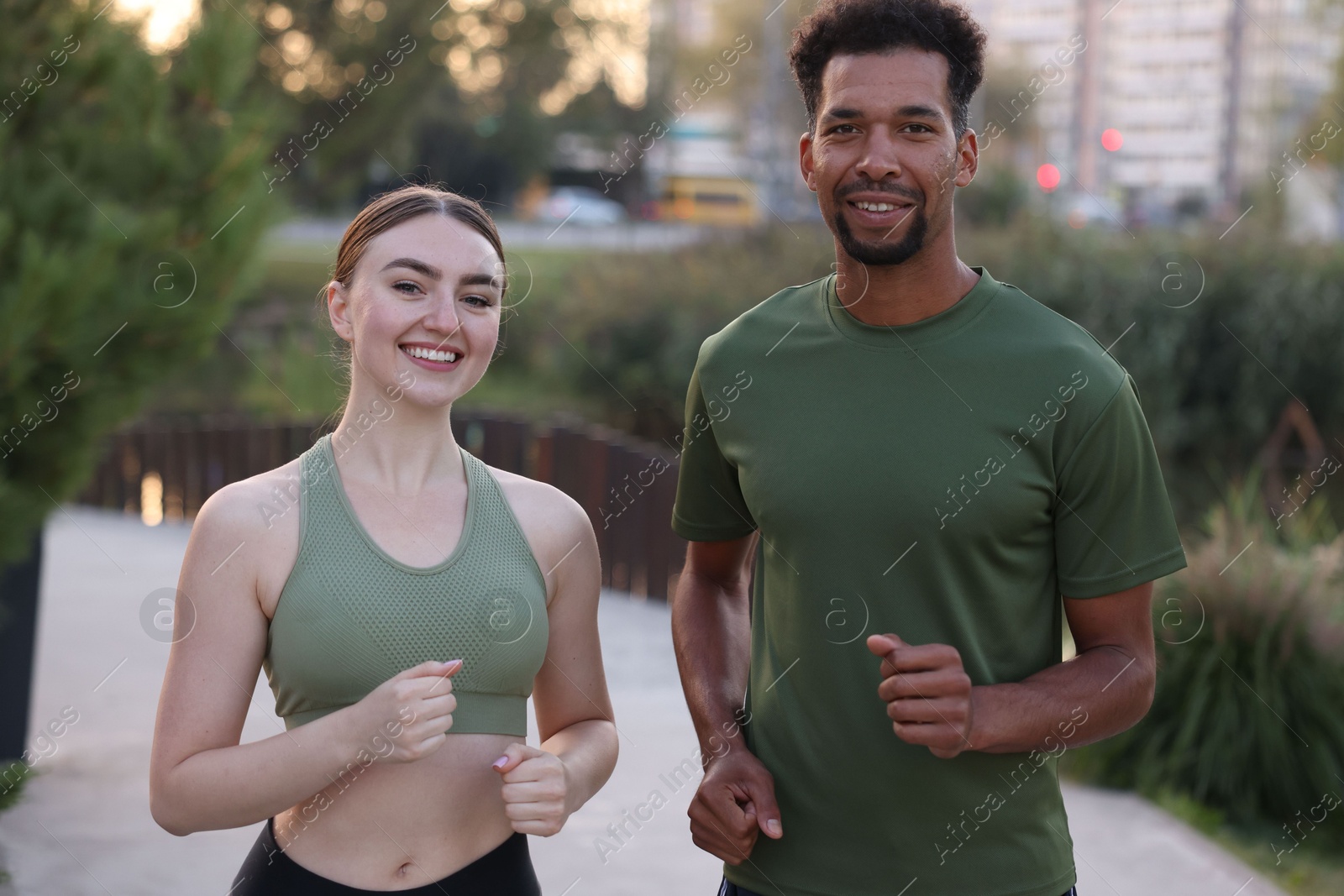 Photo of Smiling couple in sportswear running outdoors. Healthy lifestyle