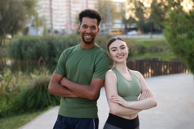 Photo of Smiling runners posing with crossed arms outdoors