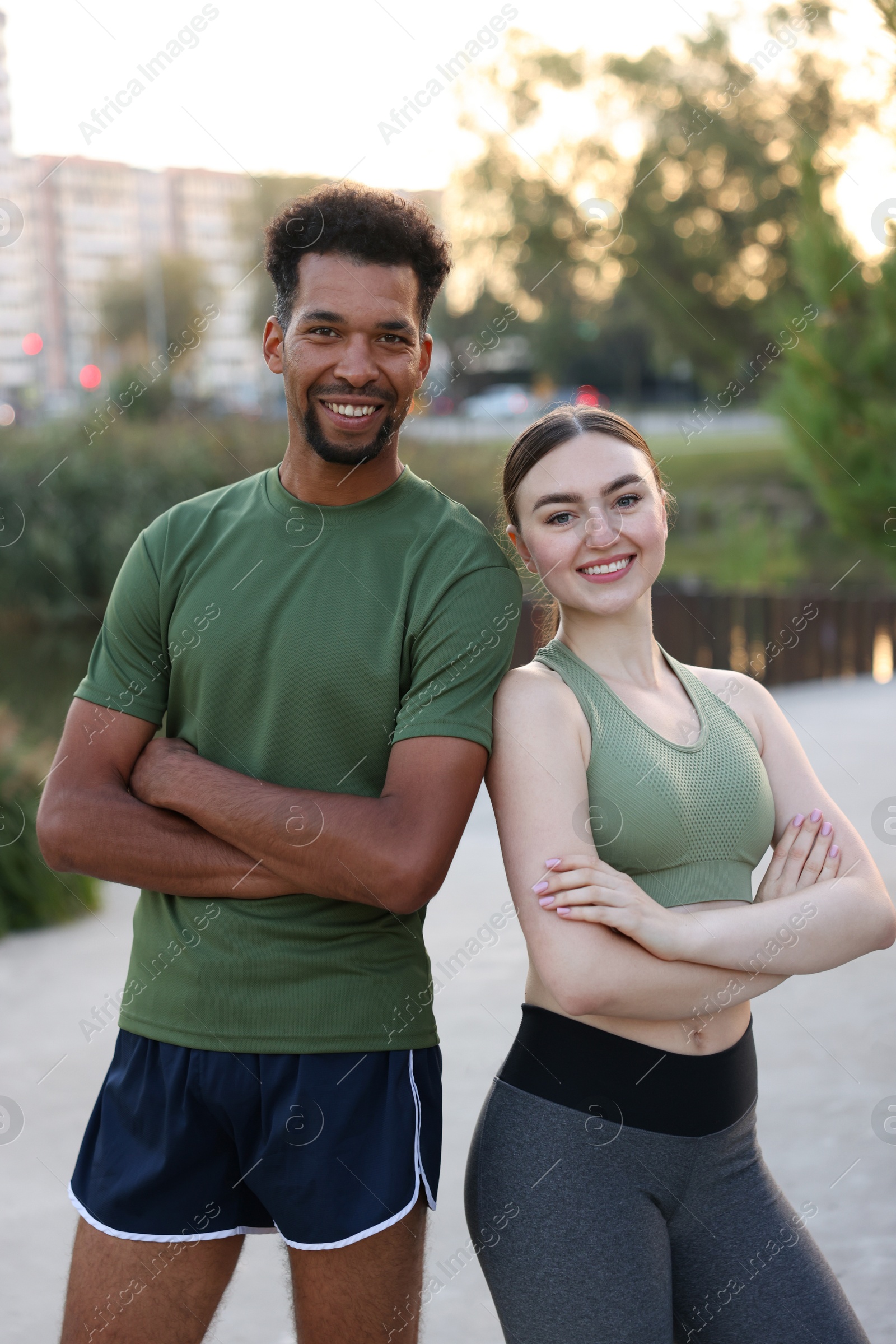 Photo of Smiling runners posing with crossed arms outdoors
