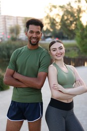 Photo of Smiling runners posing with crossed arms outdoors