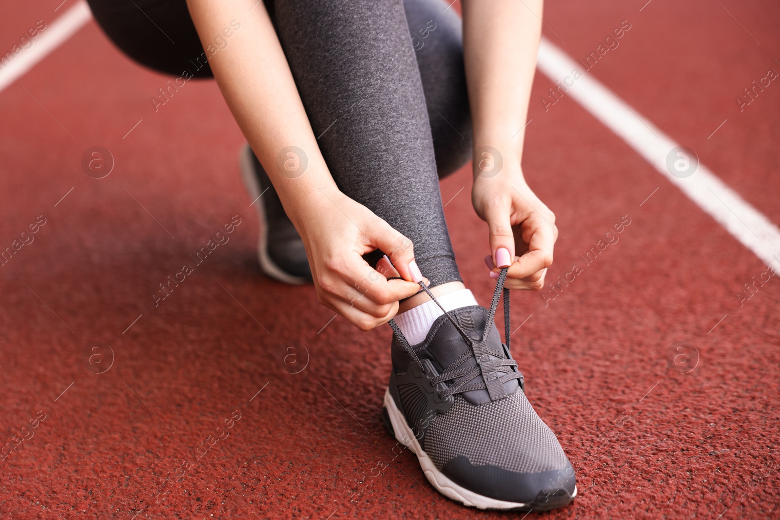 Runner tying shoelace of her sneaker at stadium, closeup Photo of Runner tying shoelace of her sneaker at stadium, closeup