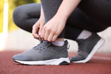 Photo of Runner tying shoelace of her sneaker outdoors, closeup
