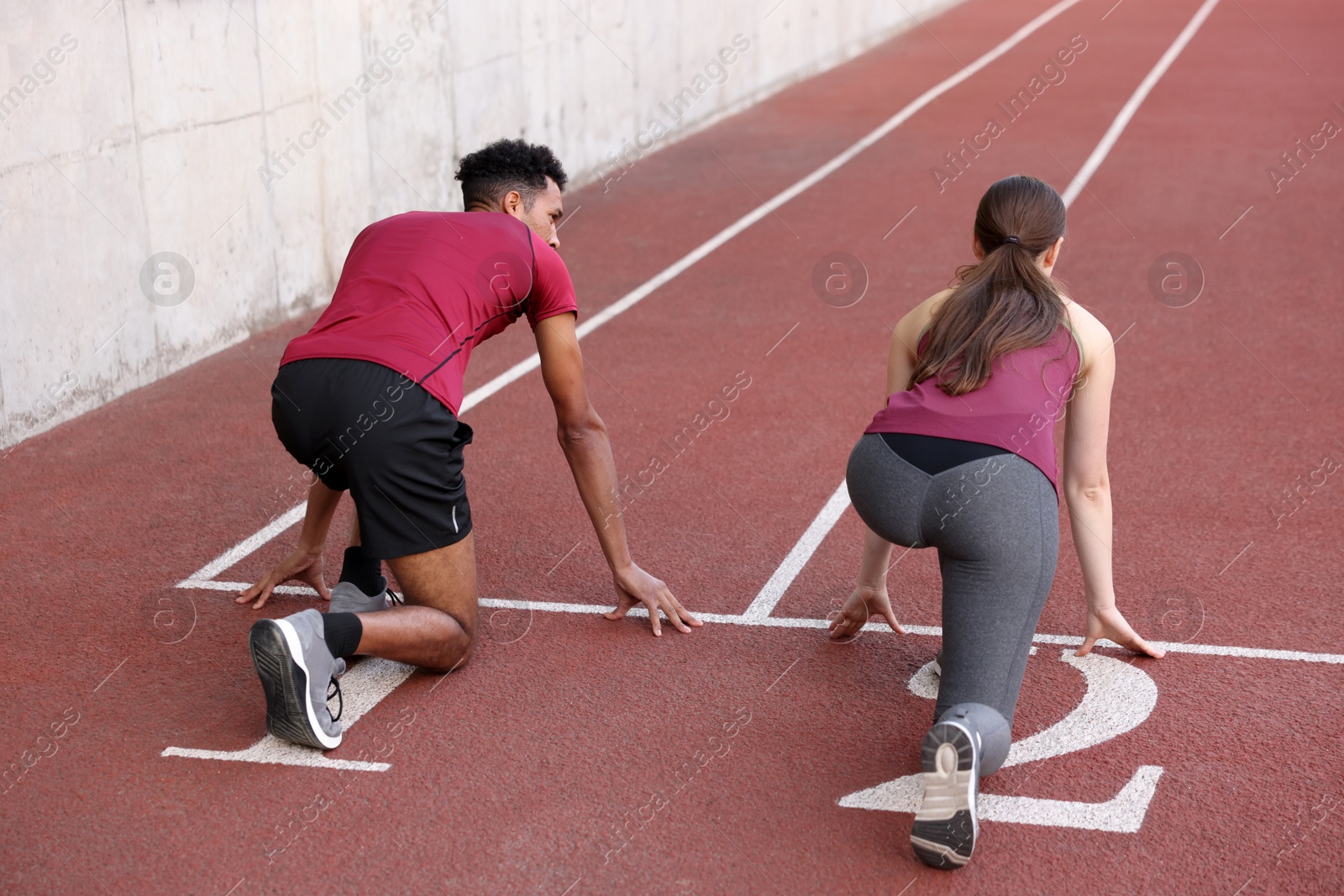 Photo of Couple in starting position for run at stadium, back view