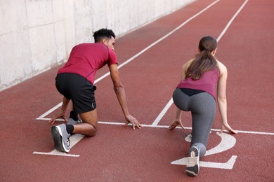 Photo of Couple in starting position for run at stadium, back view