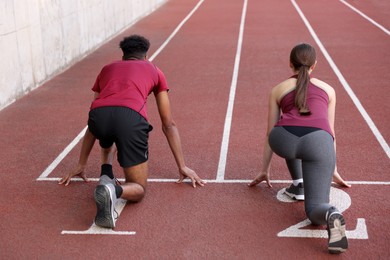 Photo of Couple in starting position for run at stadium, back view