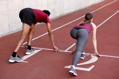 Photo of Couple in starting position for run at stadium, back view