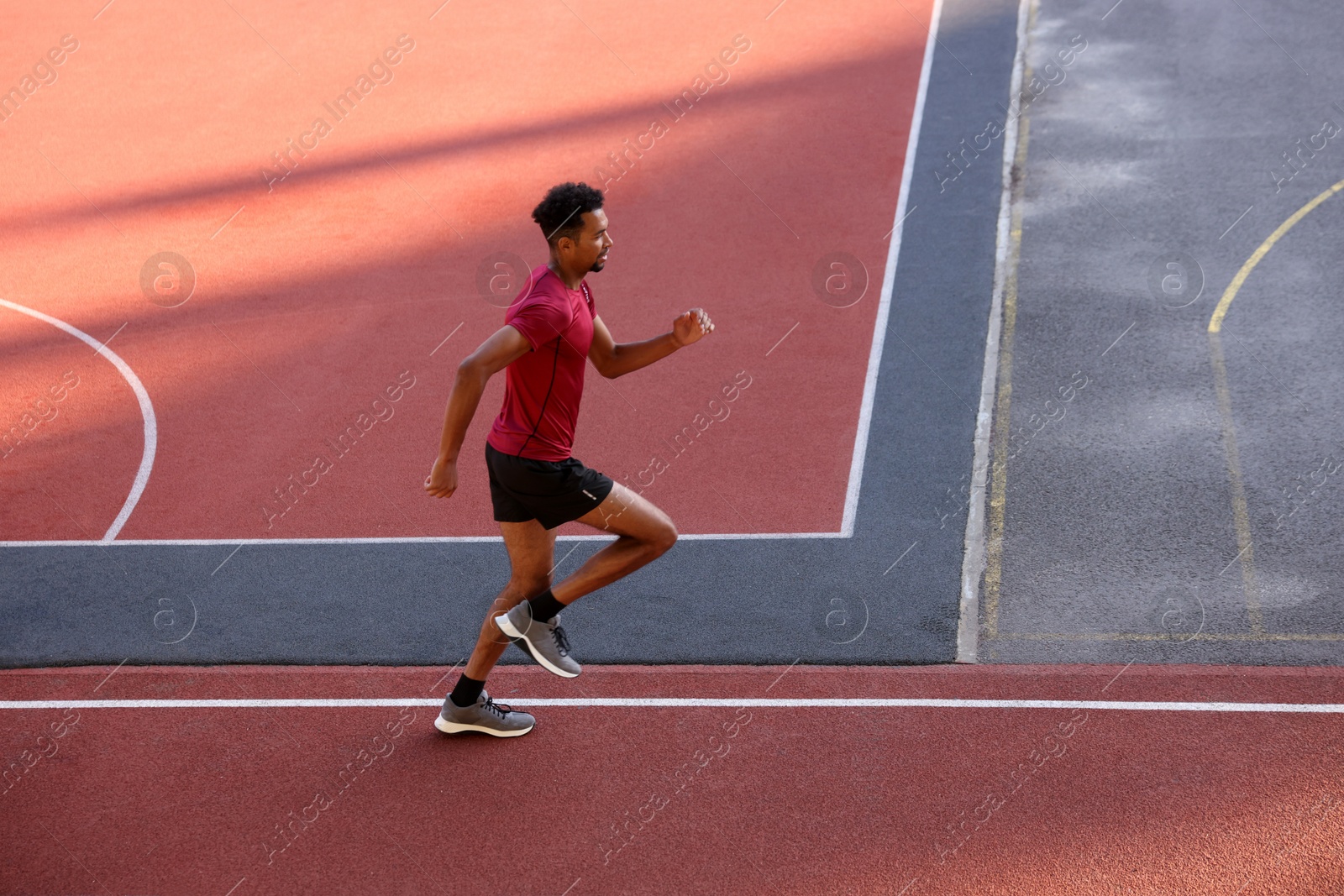 Photo of Handsome man in sportswear running at stadium