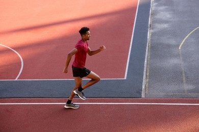 Photo of Handsome man in sportswear running at stadium