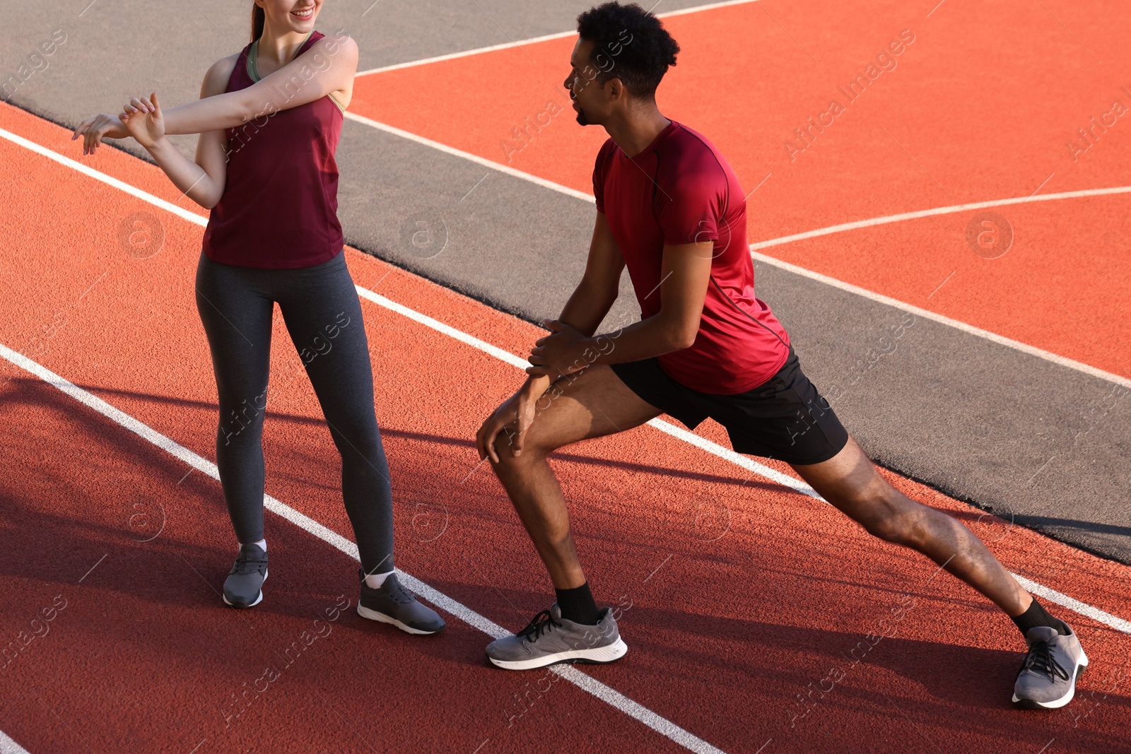 Couple in sportswear doing warm-up exercises before run at stadium, closeup Photo of Couple in sportswear doing warm-up exercises before run at stadium, closeup