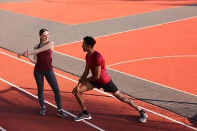 Photo of Couple in sportswear doing warm-up exercises before run at stadium
