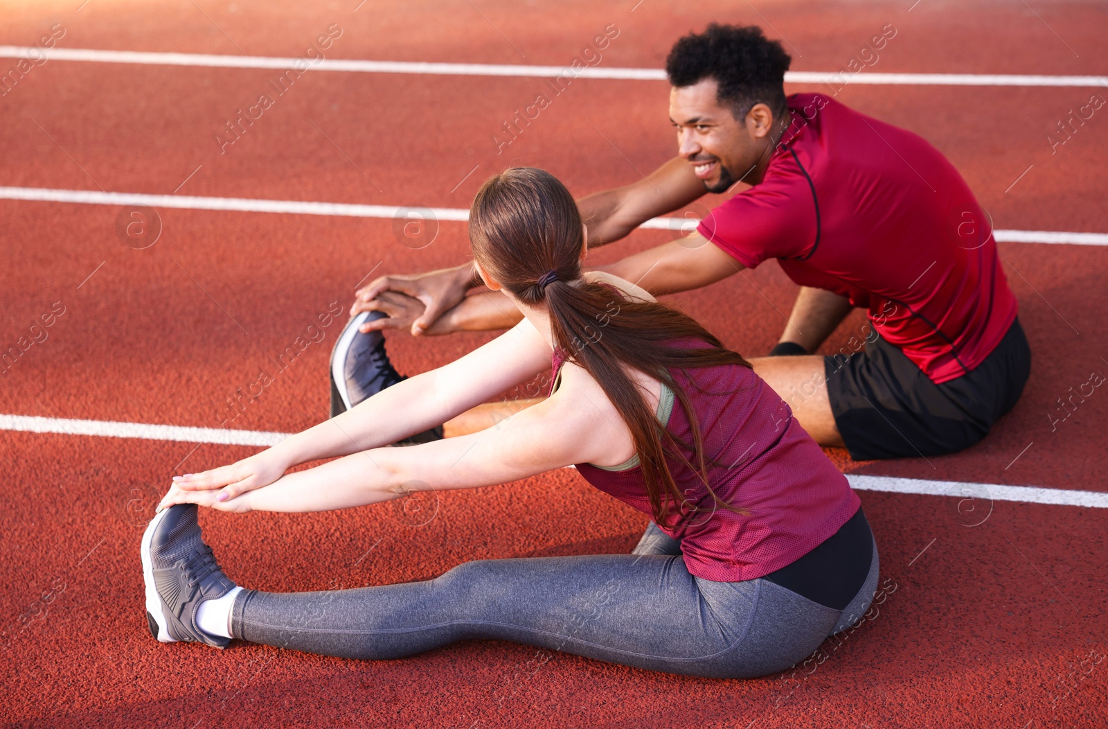 Photo of Couple in sportswear stretching before run at stadium