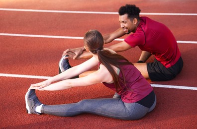 Photo of Couple in sportswear stretching before run at stadium