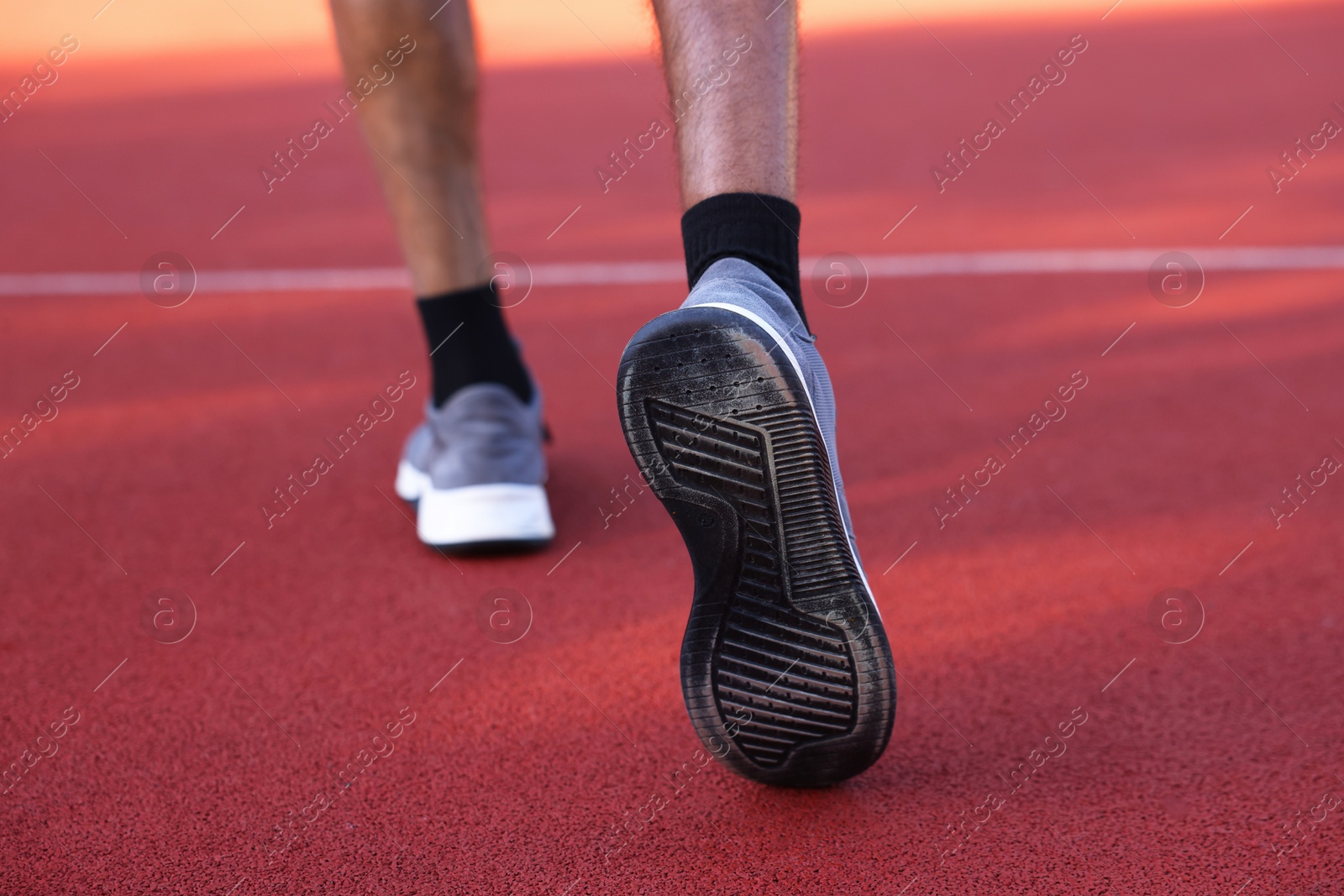 Photo of Man in sneakers running at stadium, closeup
