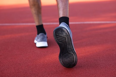 Photo of Man in sneakers running at stadium, closeup