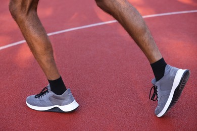 Photo of Man in sneakers running at stadium, closeup