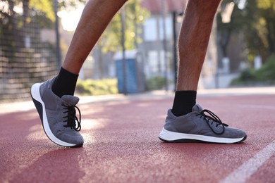 Photo of Man in sneakers running at stadium, closeup
