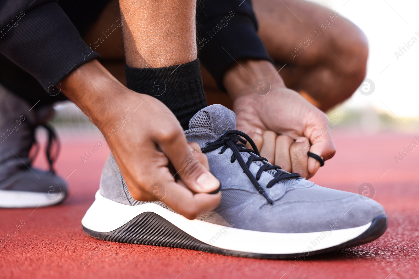Runner tying shoelace of his sneaker at stadium, closeup Photo of Runner tying shoelace of his sneaker at stadium, closeup